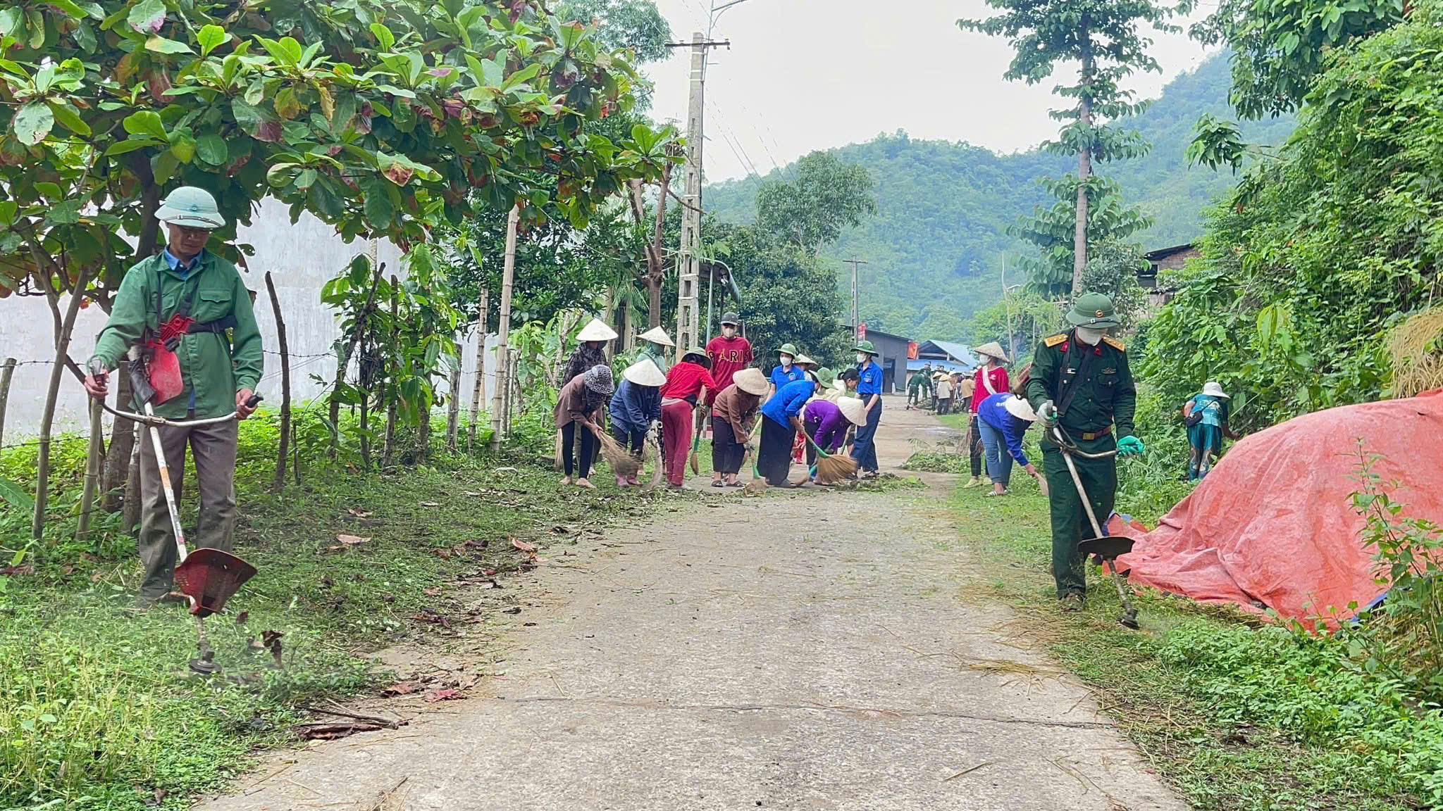 Cán bộ, nhân viên, trí thức trẻ tình nguyện của Đoàn Kinh tế - Quốc phòng 5 và Nhân dân khu phố Piềng Mòn dọn dẹp vệ sinh đường làng, ngõ xóm.