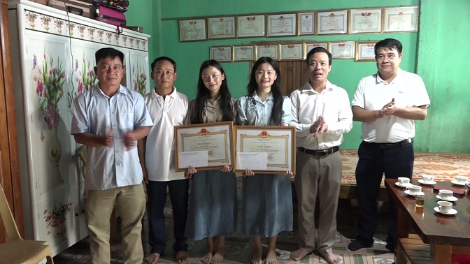 Đồng chí Mai Xuân Giang, Phó Chủ tịch UBND huyện trao giấy khen của Chủ tịch UBND huyện cho 2 học sinh Lương Thị Mai và Lương Thị Đào